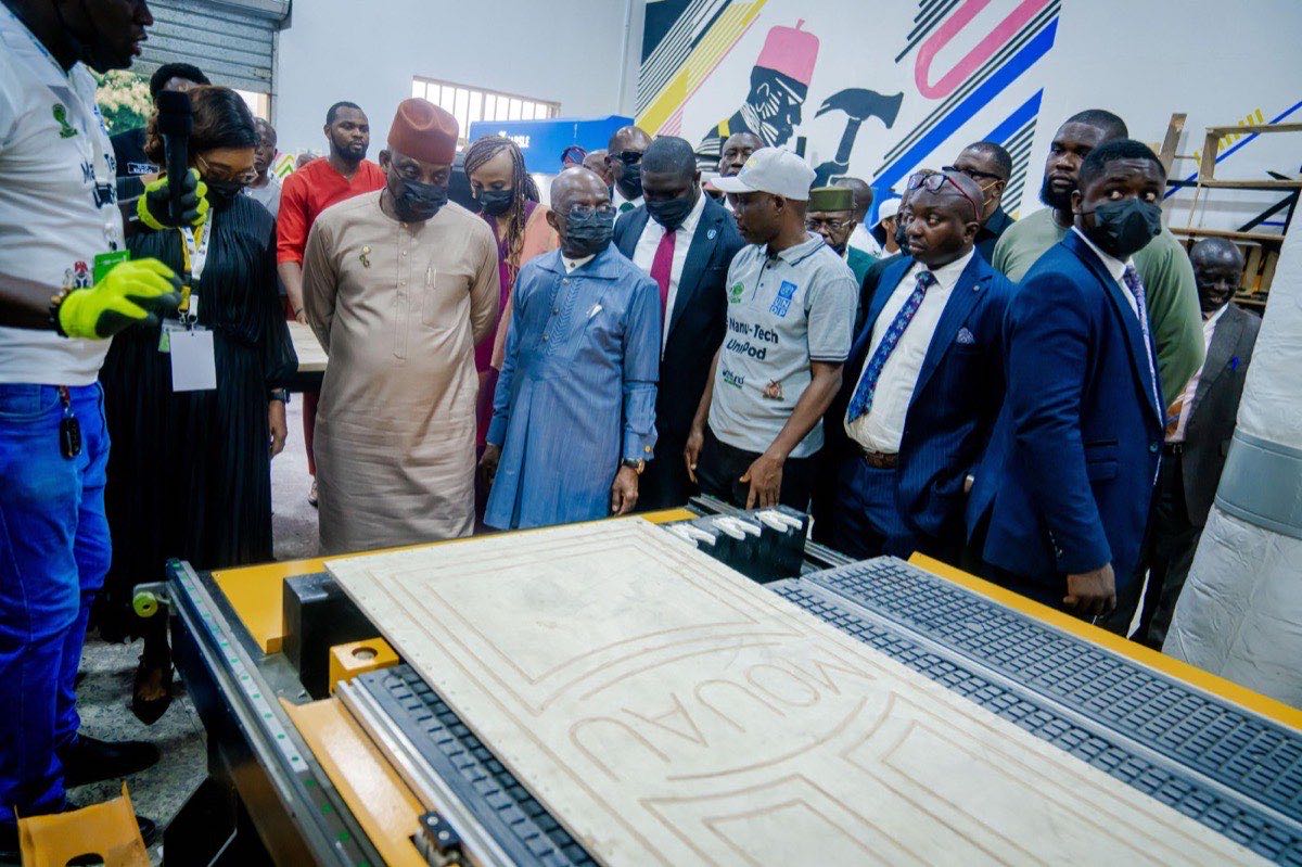 A student demonstrates fabrication equipment to visiting officials at a university innovation pod